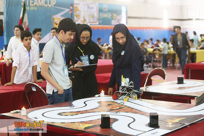 مربیان در حال داوری مسابقه رباتیک ربات امدادگر
